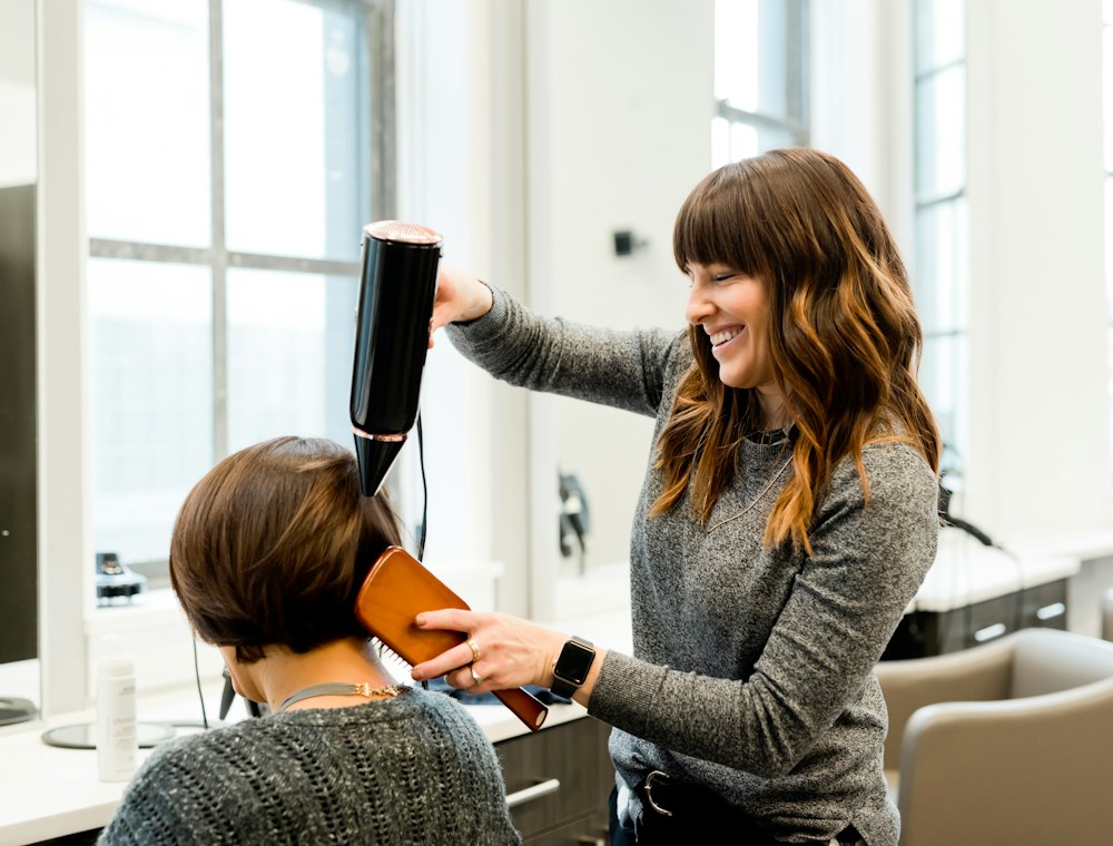 A hairdresser blow-drying a client